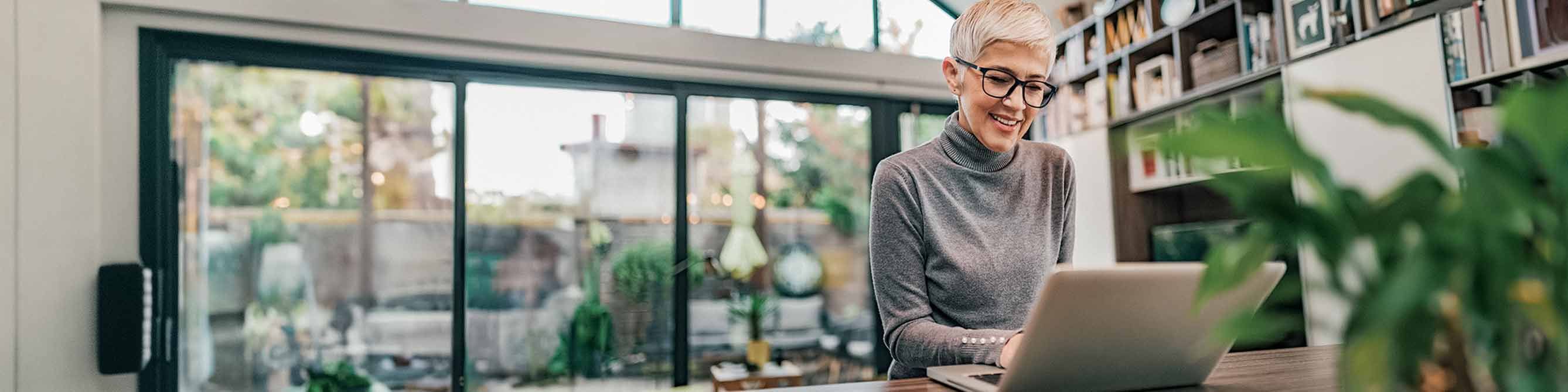 Frau mit dunkler Brille und kurzen weißen Haaren informiert sich am Laptop über die Haus- und Grundbesitzerhaftpflicht 
