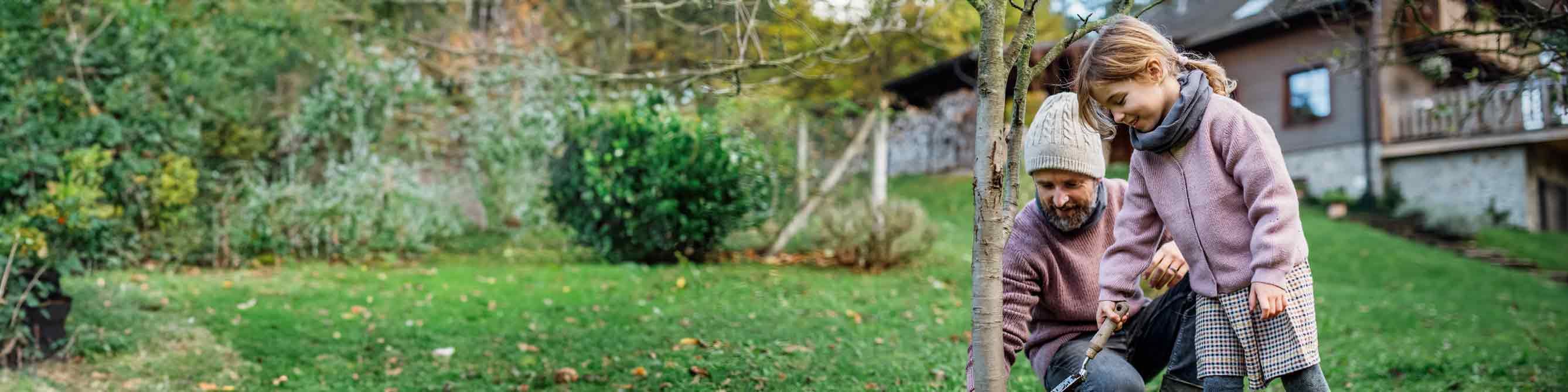 Wohngebäudeversicherung: Kunde pflanzt mit Tochter Baum vorm Eigenheim
