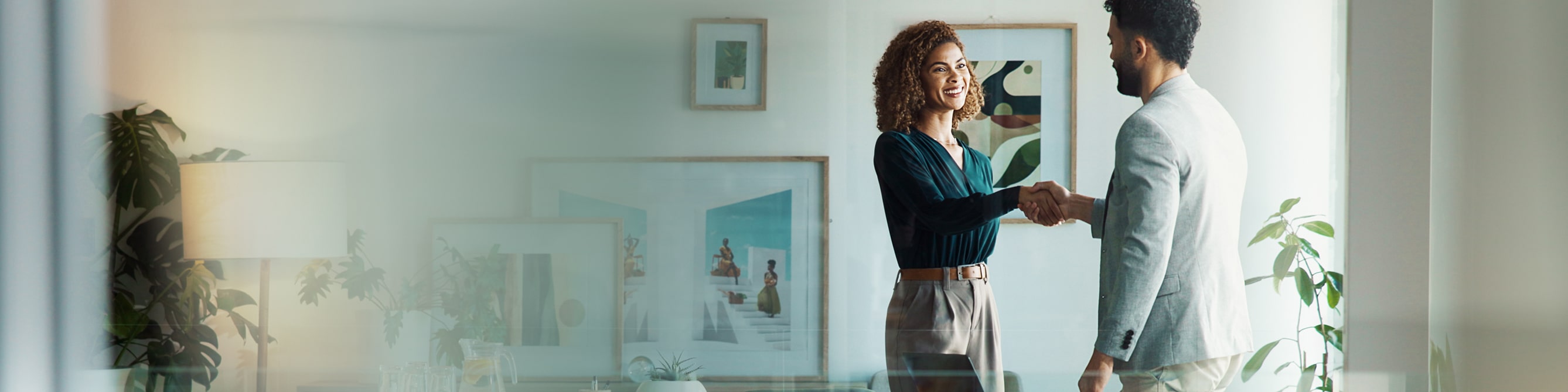 Frau und Mann schütteln sich im Büro die Hand.
