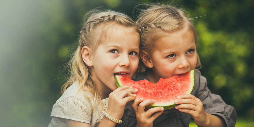 Rundum Schutz Plus: Zwei junge Mädchen knabbern an einer Wassermelone