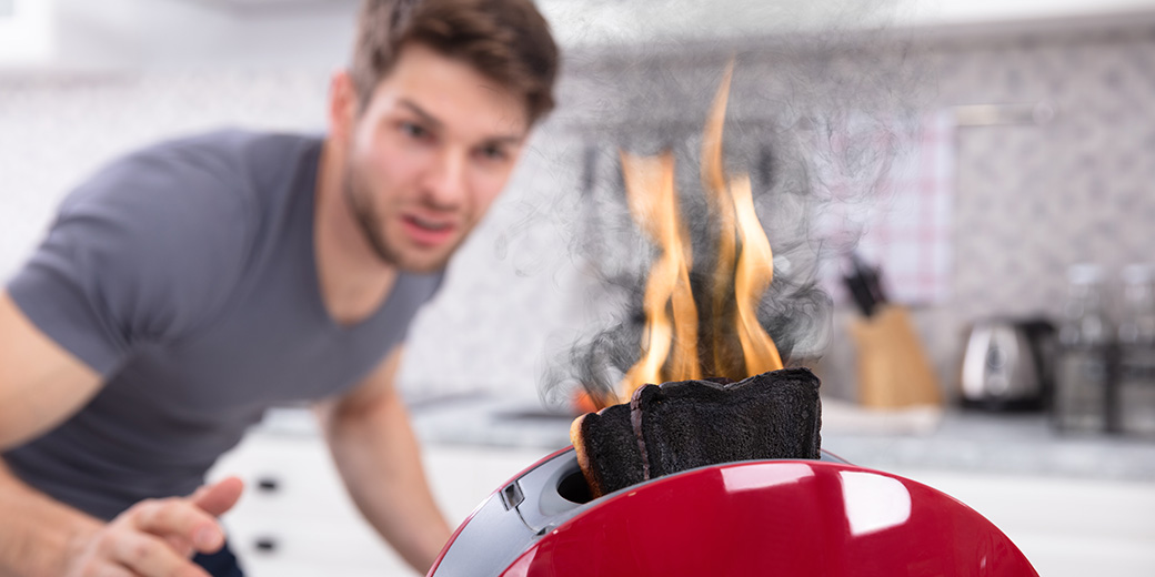 Junger Mann vor brennendem Toaster