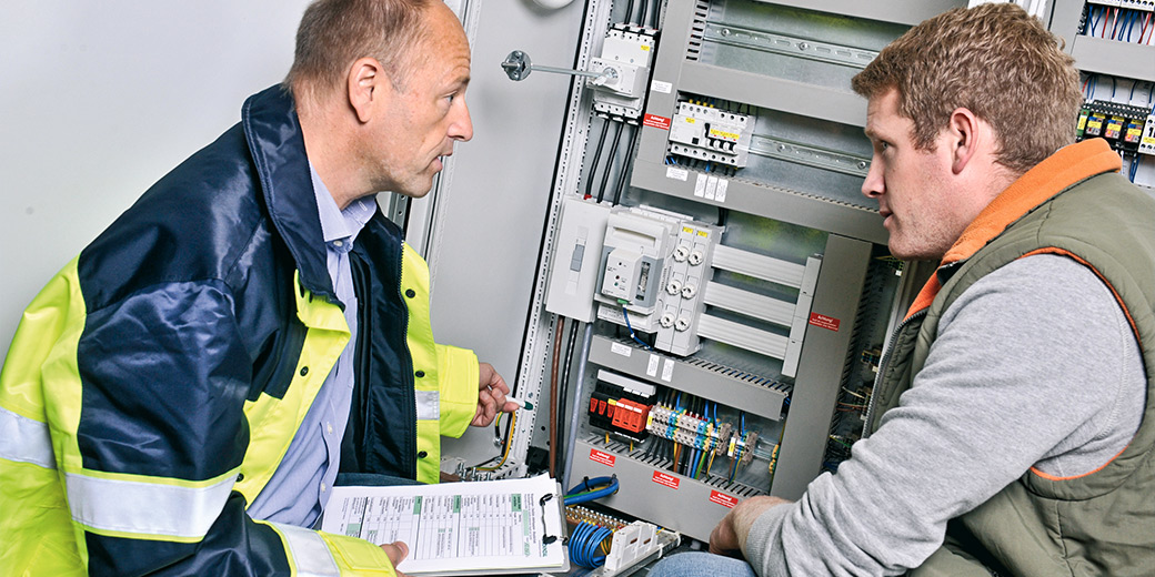 Zwei Elektriker begutachten einen Stromkasten.