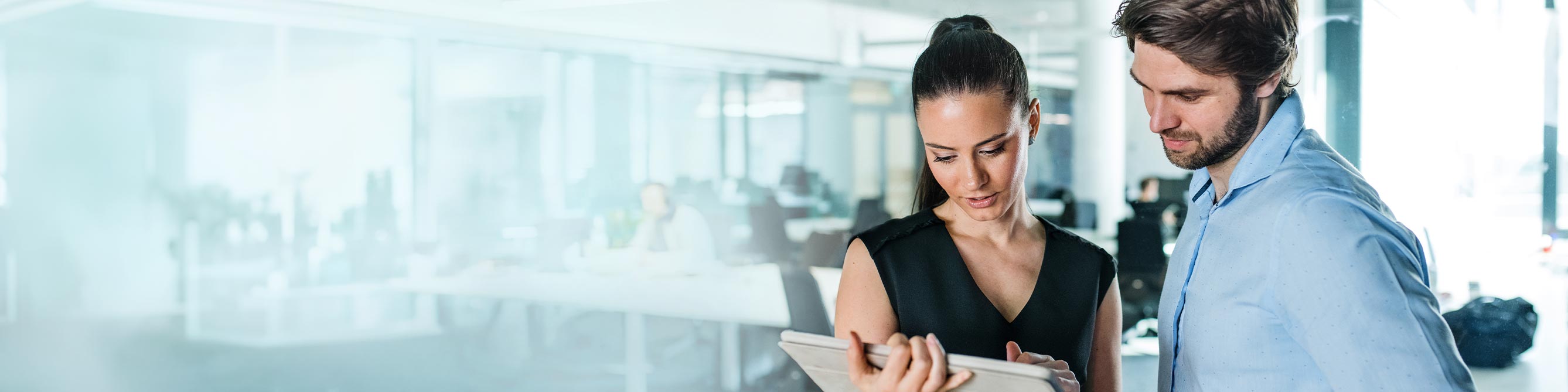 Zwei Männer stehen in einem Büro und schauen sich Akten an.