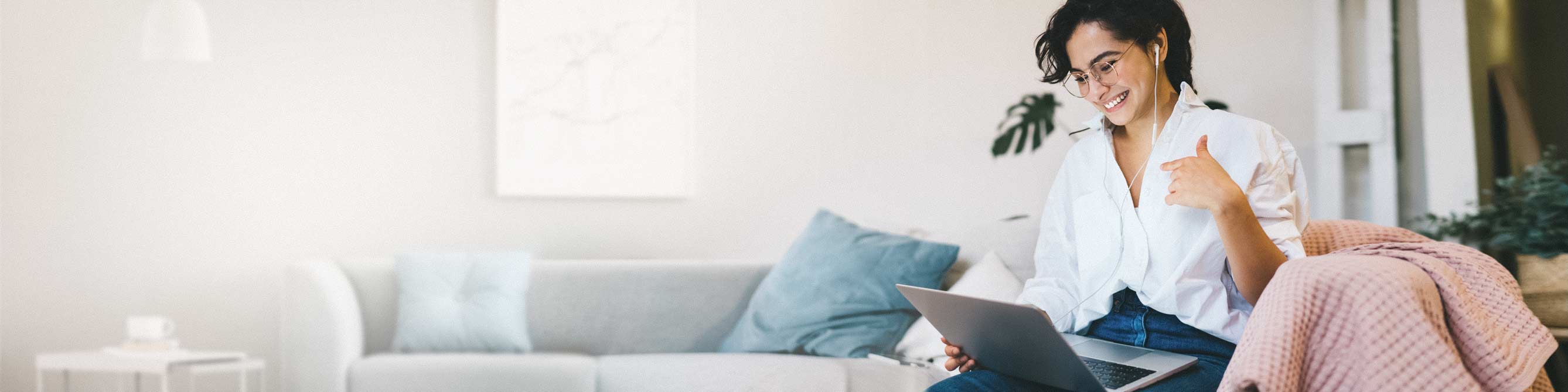 Frau mit Laptop auf grauer Couch