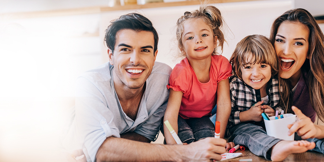 Rundum Schutz: Lächelnde Familie mit 2 Kindern