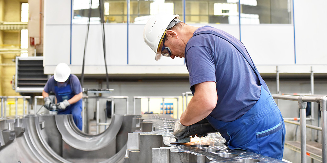 Zwei Arbeiter Schleifen eine Metallröhre
