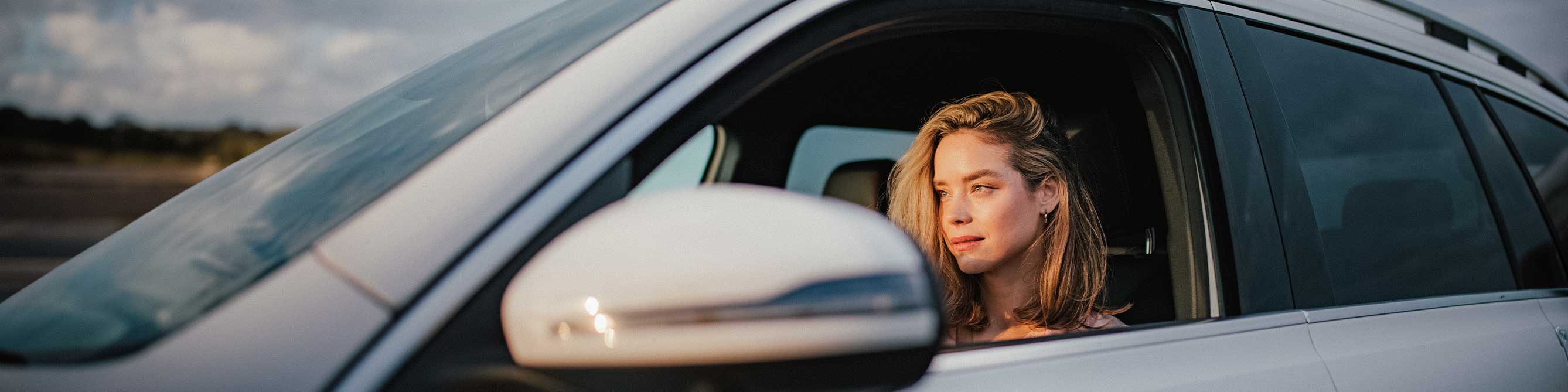 Frau sitzt im Auto am Steuer und schaut geradeaus