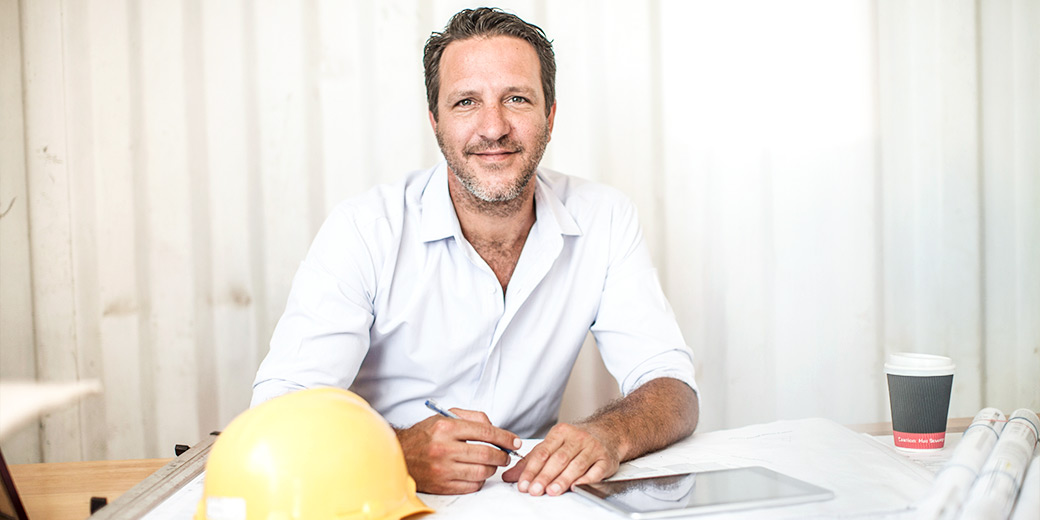 Bau- und Bauhandwerksbetriebe: Ein Bauunternehmer sitzt an einem Schreibtisch.
