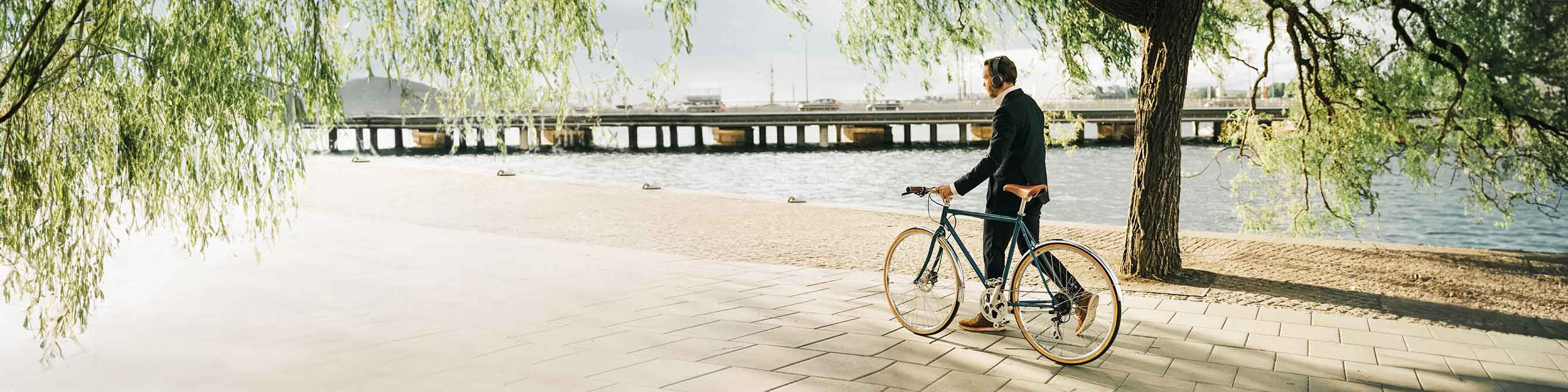 Mann schiebt sein Fahrrad am Fluss entlang