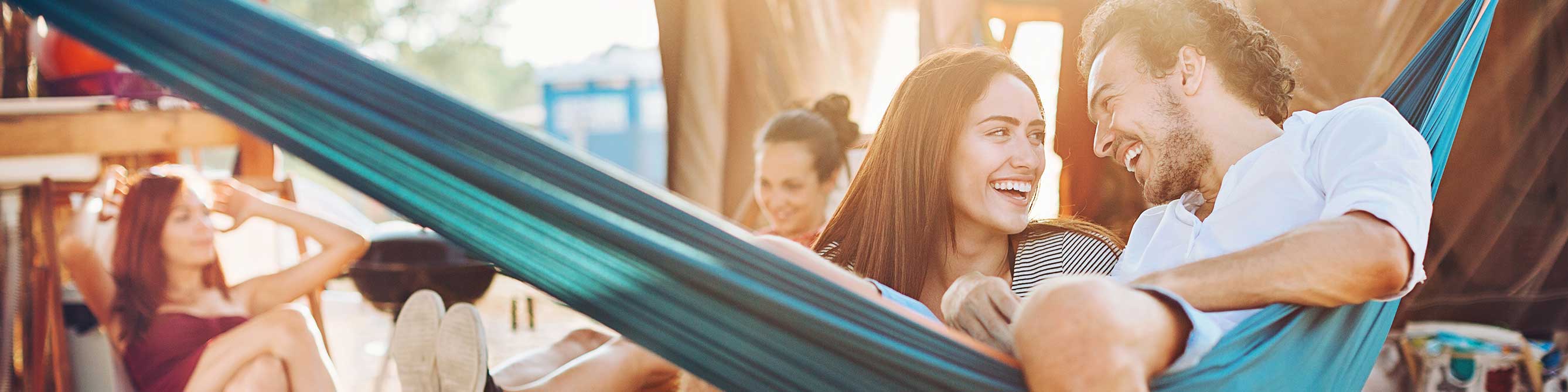 Reiseversicherung im Überblick: Pärchen in Abendsonne in der Hängematte