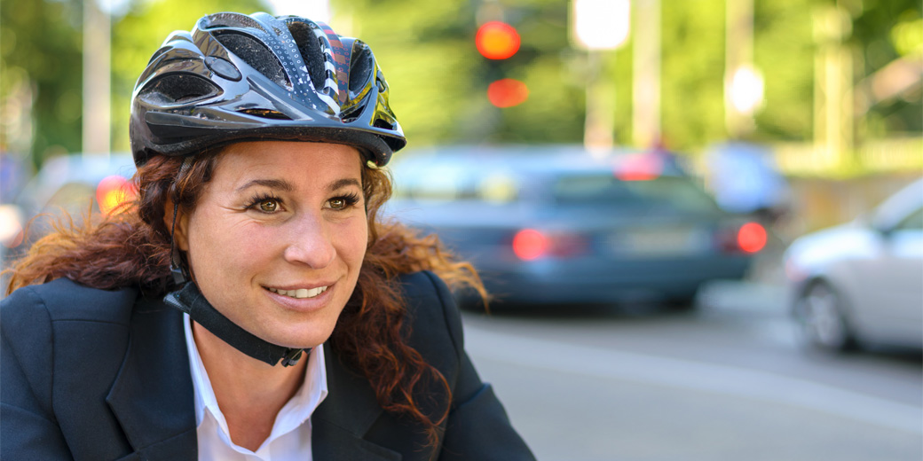 Frau mit Helm auf Fahrrad im Straßenverkehr