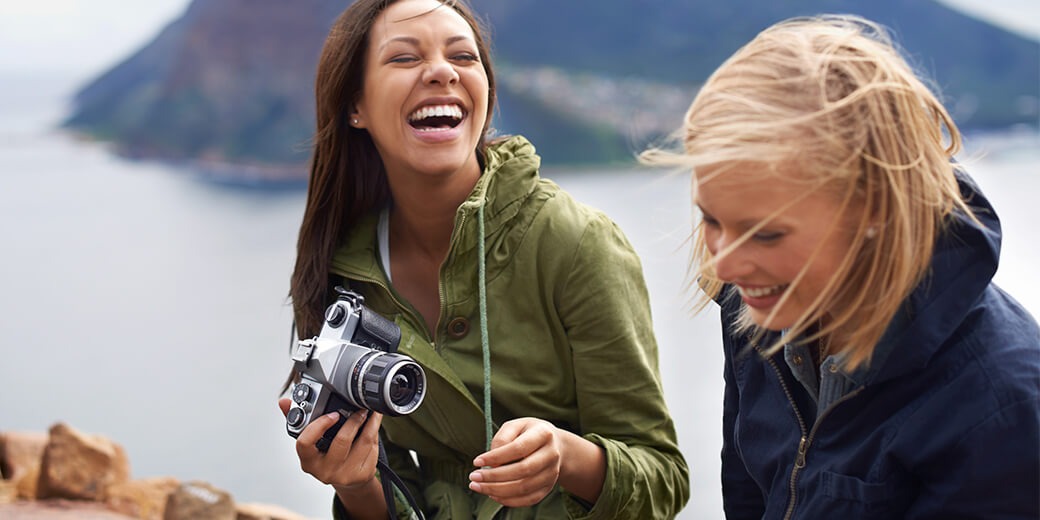Reiserücktrittsversicherung Einmalschutz: Zwei Frauen mit einer Kamera auf einem Berg