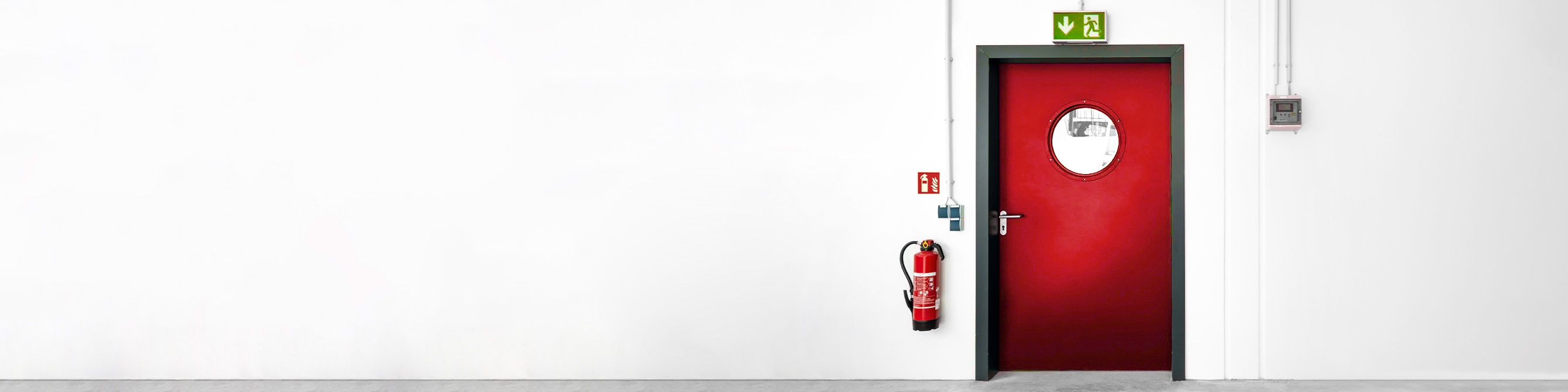 Das Bild zeigt einen an einer Wand befestigten Feuerlöscher neben einer Tür