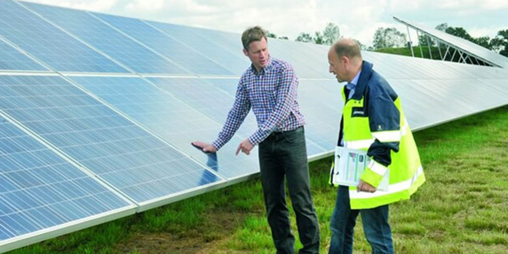 Techniker ispizieren eine Solaranlage auf einem Feld.