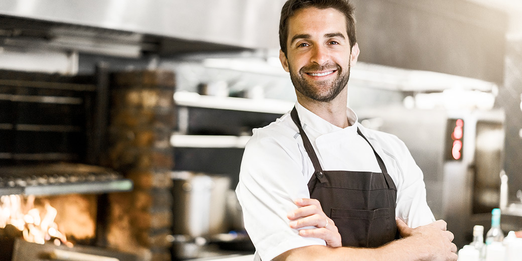 Hotel und Gastronomie: Ein Koch steht in einer Küche.