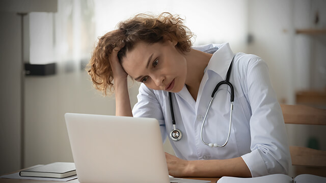 Ärztin sitzt besorgt vor Notebook