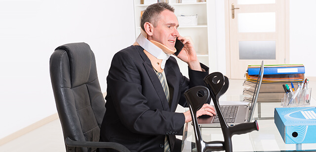 Unfallversicherung für Unternehmer: Ein Geschäftsmann sitzt am Schreibtisch und telefoniert. Er trägt eine Halskrause