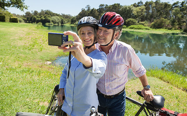 SofortRente: Ein älteres Ehepaar macht bei einem Ausflug mit dem Fahrrad ein Selfie.